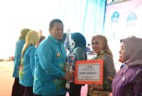 Ketua TP-PKK Lampung Timur, Yus Bariah Dawam Rahardjo saat menerima piala dari Gubernur Arinal Djunaidi. (foto: ist) 