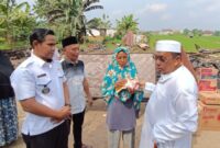 Pimpinan Ponpes Riyadhus Sholihin, KH Ismail Zulkarnain saat menyerahkan bantuan kepada korban kebakaran, Selasa (16/07/2024). (foto: ist)