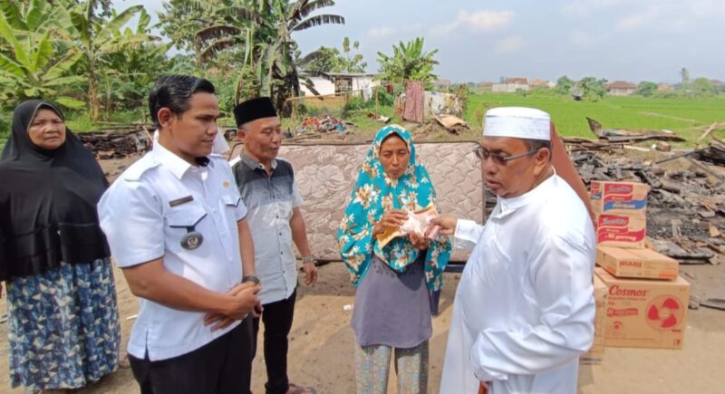 Pimpinan Ponpes Riyadhus Sholihin, KH Ismail Zulkarnain saat menyerahkan bantuan kepada korban kebakaran, Selasa (16/07/2024). (foto: ist)
