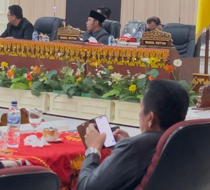 Sekda Tanggamus, Suaidi tertangkap kamera memainkan handphone saat rapat paripurna DPRD, Jumat (08/08/2025). (foto: ist)